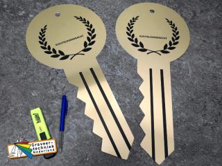 Sleuteloverdracht, grote goudkleurige aluminium plaat in de vorm van een sleutel, gegraveerd.